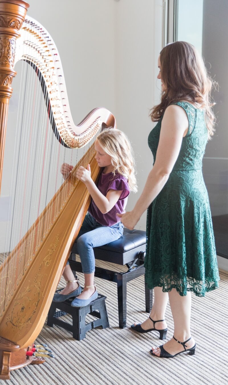 Harp lesson with teacher wearing a green dress
